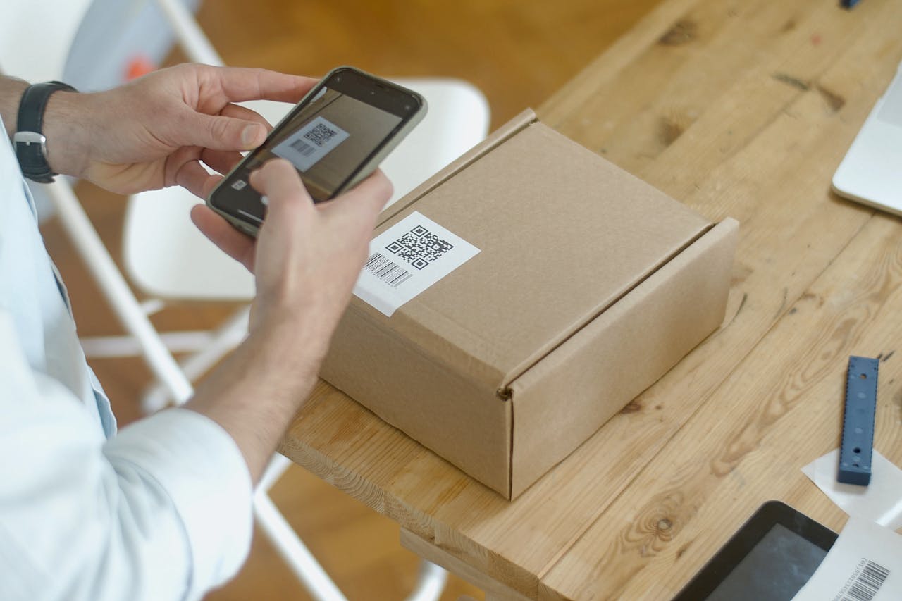 our-services-3 A person uses a smartphone to scan a QR code on a package in an online store setting.